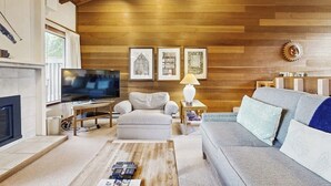 A living room with a fireplace, a television, a sofa, and a coffee table. - Rustic home with gas fireplace, pool & hot tub - ski-in/out to Dollar Mountain (Sun Valley)