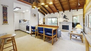 A spacious living area with a wooden ceiling, a fireplace, and a dining area with blue chairs. - Rustic home with gas fireplace, pool & hot tub - ski-in/out to Dollar Mountain (Sun Valley)
