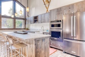 A kitchen with a large island, stainless steel appliances, and wooden cabinetry. - Ski-in/ski-out alpine condo with prime location, shared pool, hot tub, & tennis (Sun Valley)