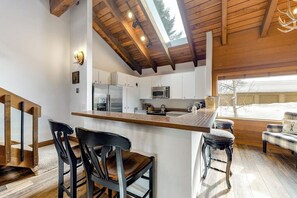 A modern kitchen with white cabinets, a wooden ceiling, and a skylight. - Ski-in/ski-out alpine condo with prime location, shared pool, hot tub, & tennis (Sun Valley)