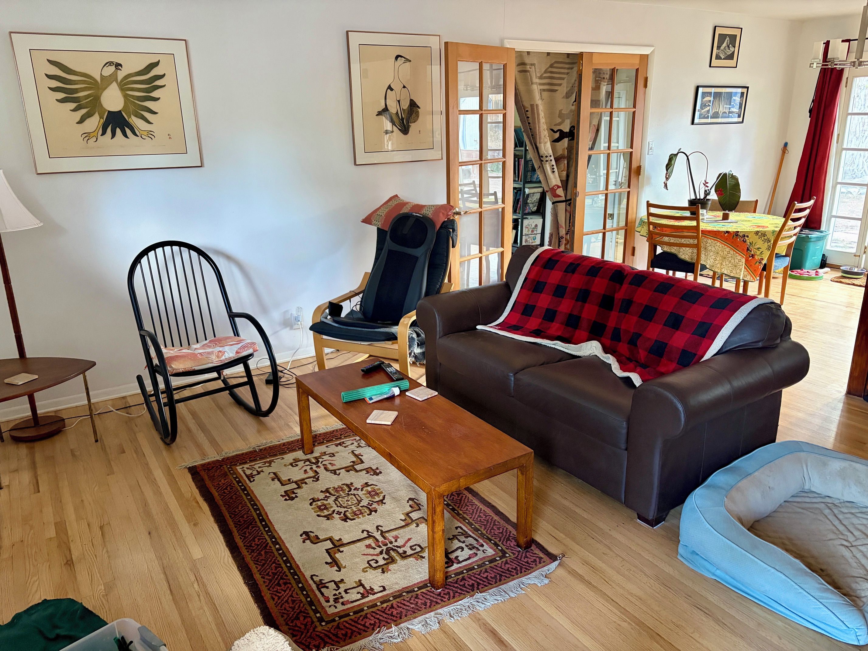 Een woonkamer met een bank, een stoel, een bijzettafeltje en een vloerkleed.