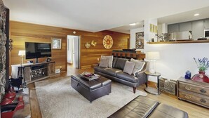 Ein modernes Wohnzimmer mit einer Couch, einem Hocker und einer Unterhaltungseinheit.
