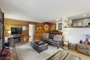 Ein modernes Wohnzimmer mit einer Couch, einem Hocker und einer Unterhaltungseinheit.