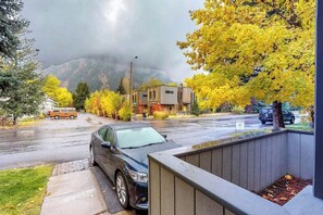 Une rue résidentielle bordée de maisons, de voitures garées et d’arbres aux feuilles d’automne.