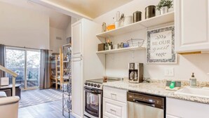 Una cucina moderna con mobili bianchi, elettrodomestici in acciaio inossidabile e un cartello con la scritta 'BE OUR guest'.