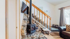 A living room with a stone wall, a fireplace, a staircase, and a sofa. - Newly updated condo - close to downtown Ketchum & the ski lifts (Ketchum)