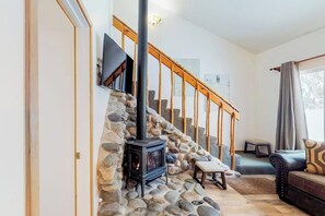 Ein Wohnzimmer mit Steinwand, Kamin, Treppe und einer Couch.
