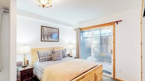 A bedroom with a bed, bedside tables, a lamp, a framed picture, and a sliding glass door. - Newly updated condo - close to downtown Ketchum & the ski lifts (Ketchum)
