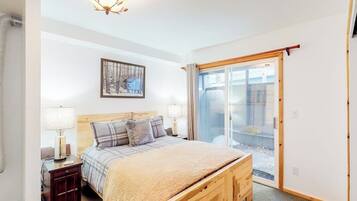 A bedroom with a bed, bedside tables, a lamp, a framed picture, and a sliding glass door.