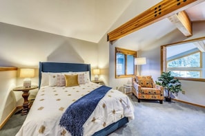 A bedroom with a bed, bedside tables, a chair, a lamp, and a window.