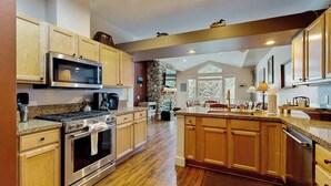 Une cuisine spacieuse dotée d’armoires en bois, d’un plan de travail en granit, d’un four encastré et d’un grand îlot central avec un évier.