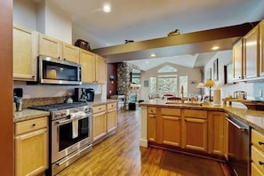 A spacious kitchen with wooden cabinets, a granite countertop, a built-in oven, and a large island with a sink.