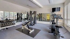 Une salle de sport équipée de machines d’exercice, d’haltères et d’un tapis de course.