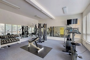 A gym with exercise equipment, dumbbells, and a treadmill.