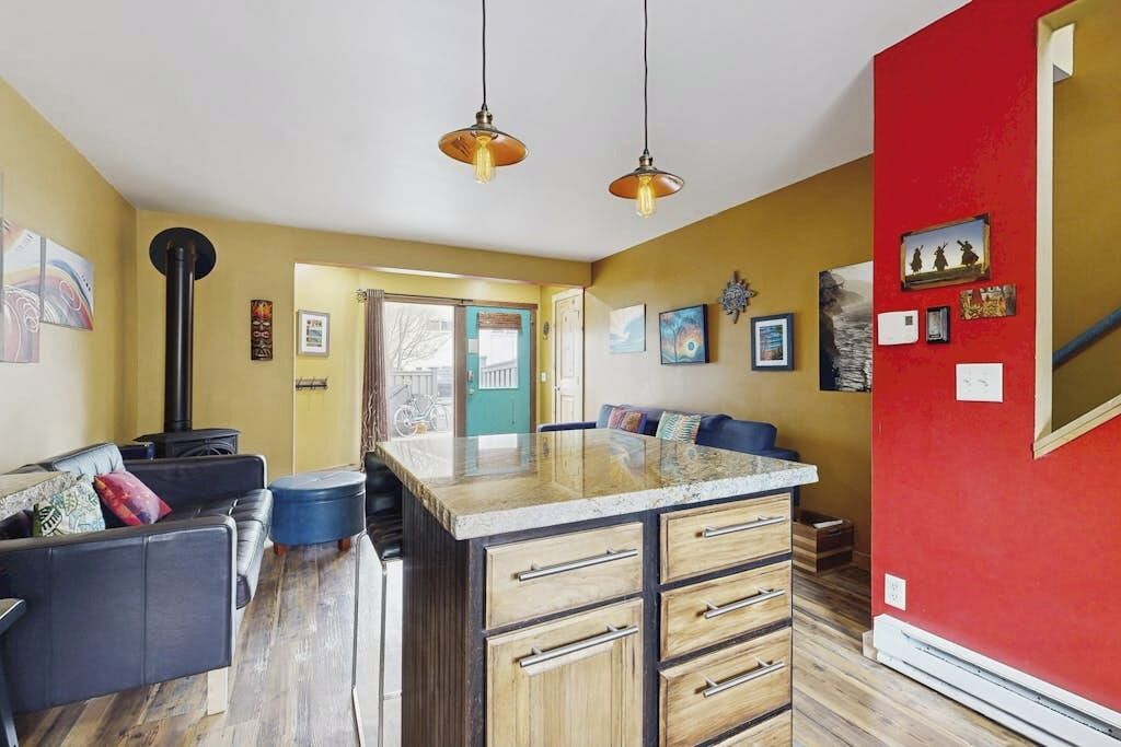 Una cocina con isla central, armarios de madera e iluminación colgante.