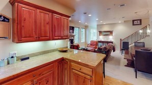 A spacious kitchen with wooden cabinets, a granite countertop, and a dining area with a staircase. - Comfortable, centrally-located condo close to skiing, hiking, & downtown (Ketchum)