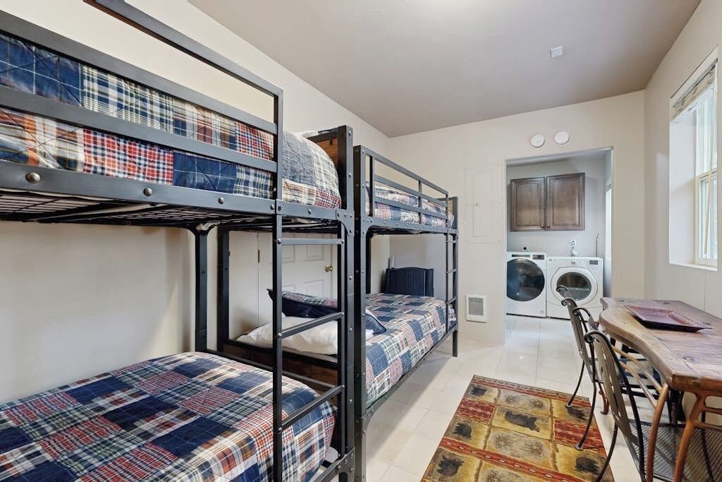 A dormitory room with bunk beds, a washing machine, and a dining area.