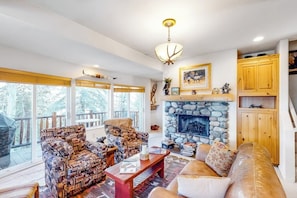 Un salon chaleureux avec une cheminée en pierre, des meubles en bois et de grandes fenêtres.