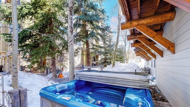 Een hottub in een besneeuwde buitenomgeving met houten balken en bomen.
