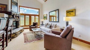 Un salón espacioso con chimenea de piedra, ventanas amplias y una zona de estar acogedora.