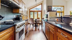 Una cocina con armarios de madera, una estufa y un comedor con sillas y una mesa.