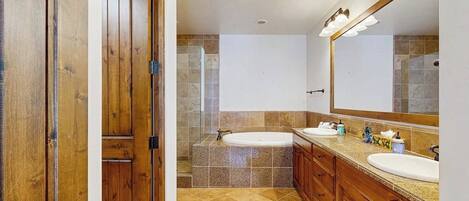 Ein Badezimmer mit Holzausstattung, einem großen Spiegel, zwei Waschbecken, einer Badewanne und einer Dusche.