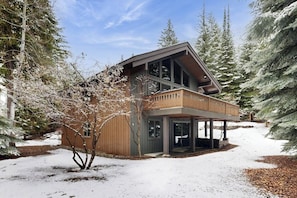 Ein modernes Haus mit Holzfassade, großen Fenstern und einer überdachten Veranda.