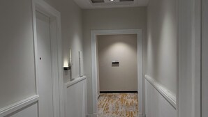 Un couloir aux murs blancs, doté d’un tapis à motifs et d’un plafond pourvu d’un éclairage encastré.