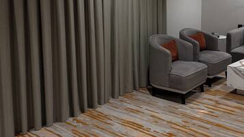 A modern room with grey curtains, a patterned carpet, and two grey armchairs with orange cushions.