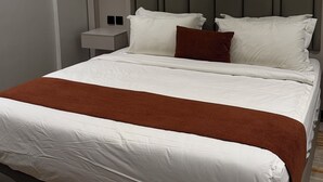 Une chambre d’hôtel moderne avec un grand lit, une table de chevet et une tête de lit.
