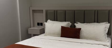 Una habitación de hotel moderna con una cama grande, una mesita de noche y un cabecero.