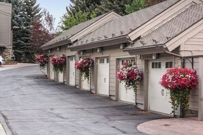 Eine Reihe einstöckiger Gebäude mit Garagentoren, jedes mit einem Blumenkorb.