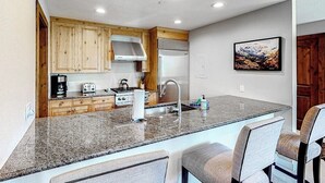 Eine Küche mit Granit-Arbeitsplatten, Holzschränken, einem Edelstahl-Kühlschrank und einem Einbauofen.