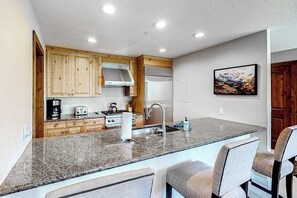 Eine Küche mit Granit-Arbeitsplatten, Holzschränken, einem Edelstahl-Kühlschrank und einem Einbauofen.