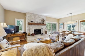 A living room with a fireplace, a television, and a sofa. - Golf course condo with ski shuttle, shared pools, & hot tub (Sun Valley)