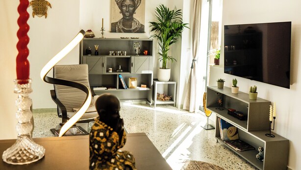 A modern living room with a sofa, a TV, a bookshelf, and a decorative plant. - Athens Center Apartment near Metro & Attractions (Athina)