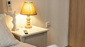 A hotel room with a neatly made bed, a bedside lamp, a telephone, and a small statue on the nightstand. - Athens Center Apartment near Metro & Attractions (Athina)