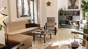 A modern living room with a sofa, armchair, coffee table, and a bookshelf. - Athens Center Apartment near Metro & Attractions (Athina)