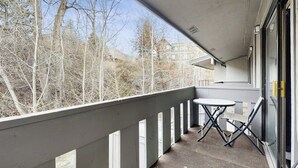 Een balkon met een tafel en stoelen, met uitzicht op een bebost gebied.