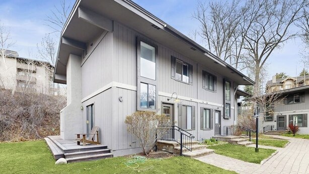 Een modern gebouw met twee verdiepingen, een plat dak, grote ramen en een kleine voortuin.