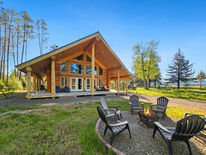 Eine Blockhütte mit überdachter Veranda, Sitzgelegenheiten im Freien und einem Feuerkorb.