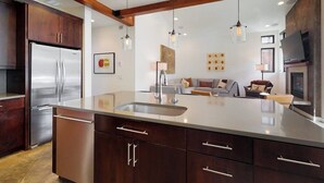 Una cocina moderna con una isla grande, electrodomésticos de acero inoxidable e iluminación colgante.