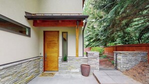 Una casa moderna con fachada de piedra, una puerta de madera y un muro de piedra.