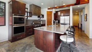 Una cocina moderna con electrodomésticos de acero inoxidable, una isla central con taburetes y armarios de madera.