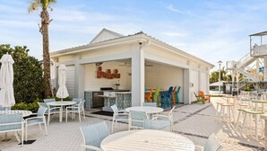 An outdoor seating area with white tables and chairs, a covered patio, and a sign that reads "RUMBRELLI". - 5 BD/ 4.5 BA Windsor Cay (1276 BP) (Clermont)