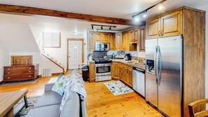 Una cocina compacta con armarios de madera, un refrigerador de acero inoxidable y un microondas.