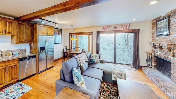 Una cocina moderna con armarios de madera y electrodomésticos de acero inoxidable, un espacio de descanso acogedor con sofá y cojines, y una chimenea.