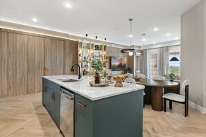 Una cocina moderna con una isla central, electrodomésticos integrados y un comedor con una mesa redonda y sillas.