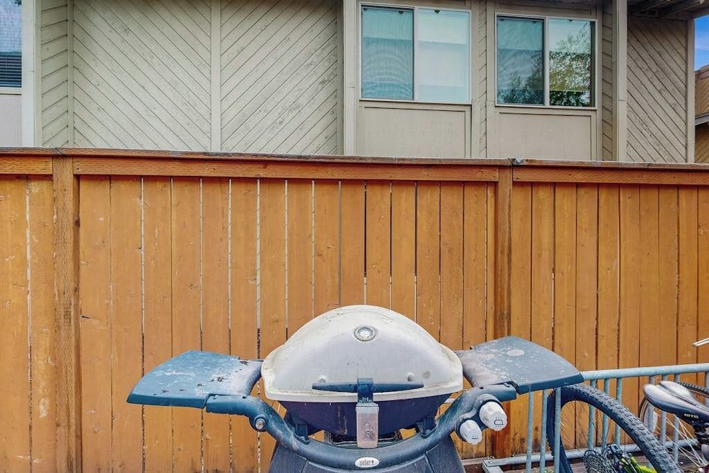 A stationary object with a handlebar, a protective cover, and a seat, positioned against a wooden fence and a building with windows.