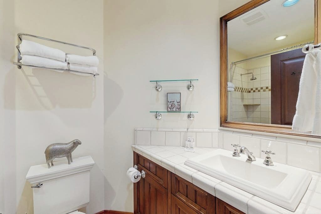 Een badkamer met toilet, wastafel, spiegel en handdoekhouder.